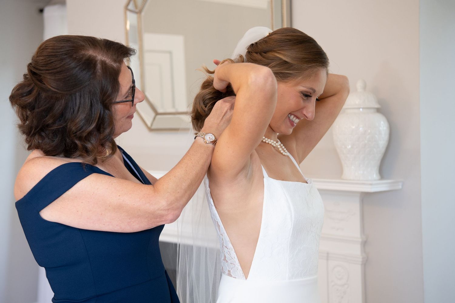 Someone helps adjust a white wedding dress during final preparations before a ceremony.