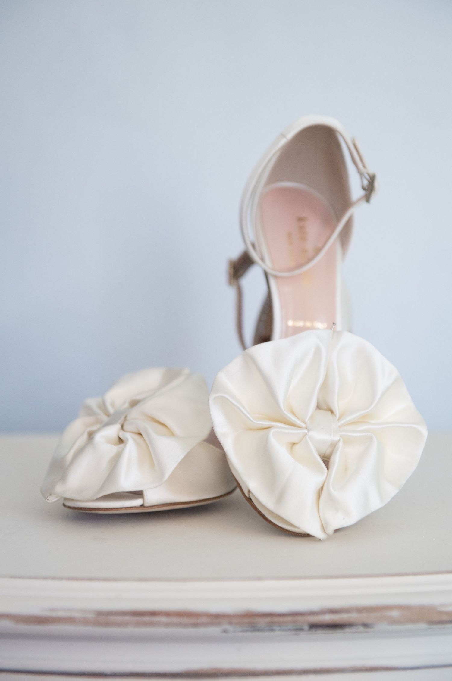Elegant white satin bridal shoes with delicate bow details photographed from different angles on a light background.