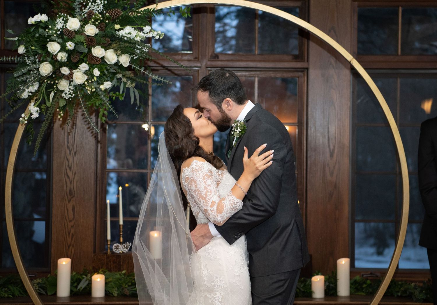 A romantic first dance moment between newlyweds under an elegant gold arch with white floral decorations.
