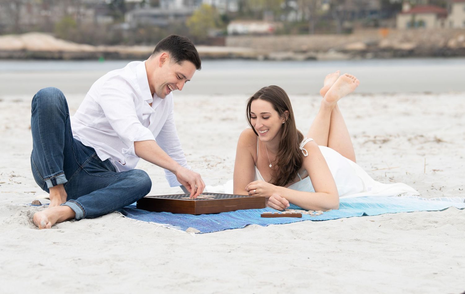Five connected images showing people lying on a sandy beach during a romantic casual photo session.