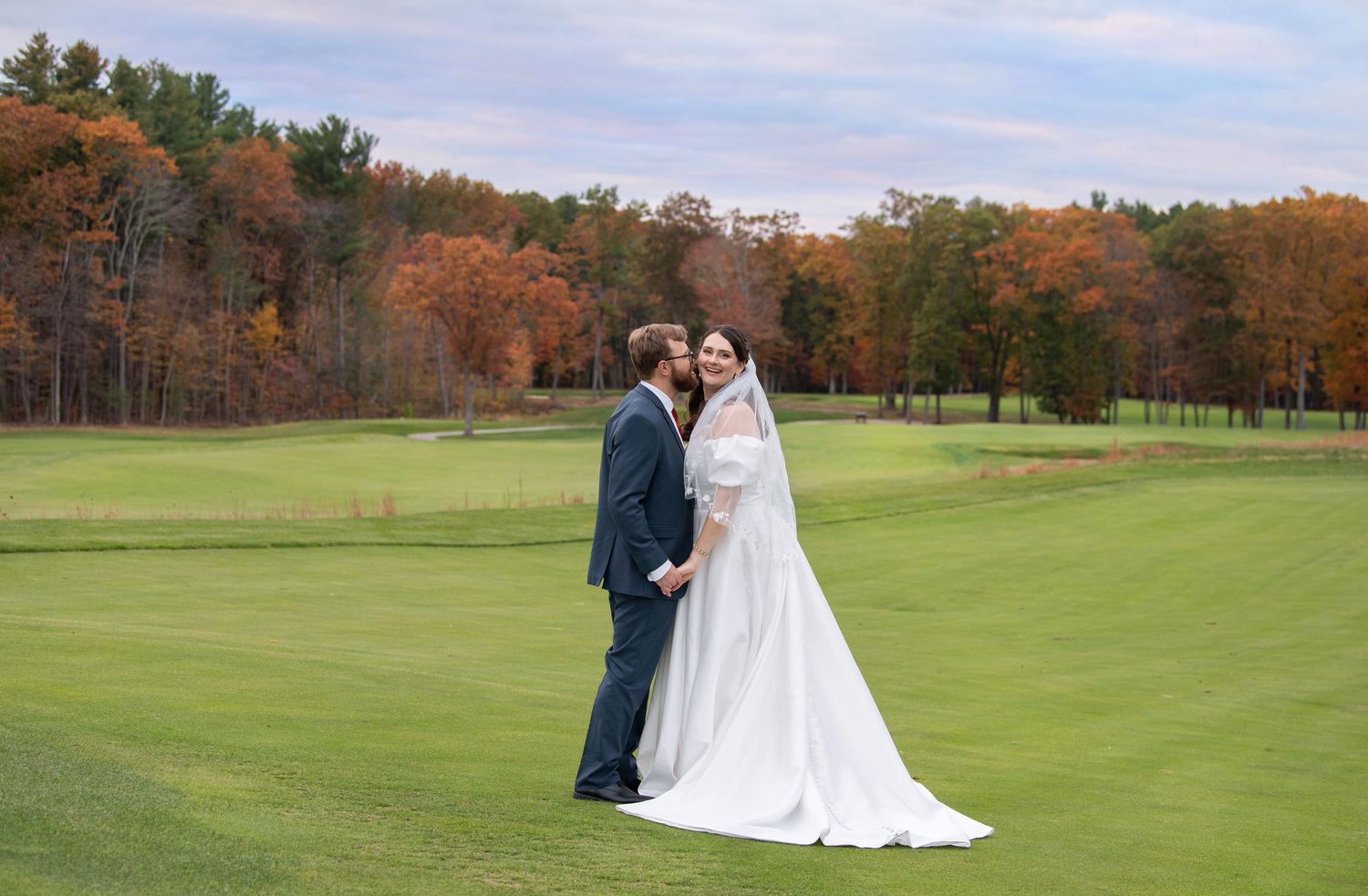 A scenic golf course fairway in autumn with vibrant fall foliage surrounding the manicured green grass.
