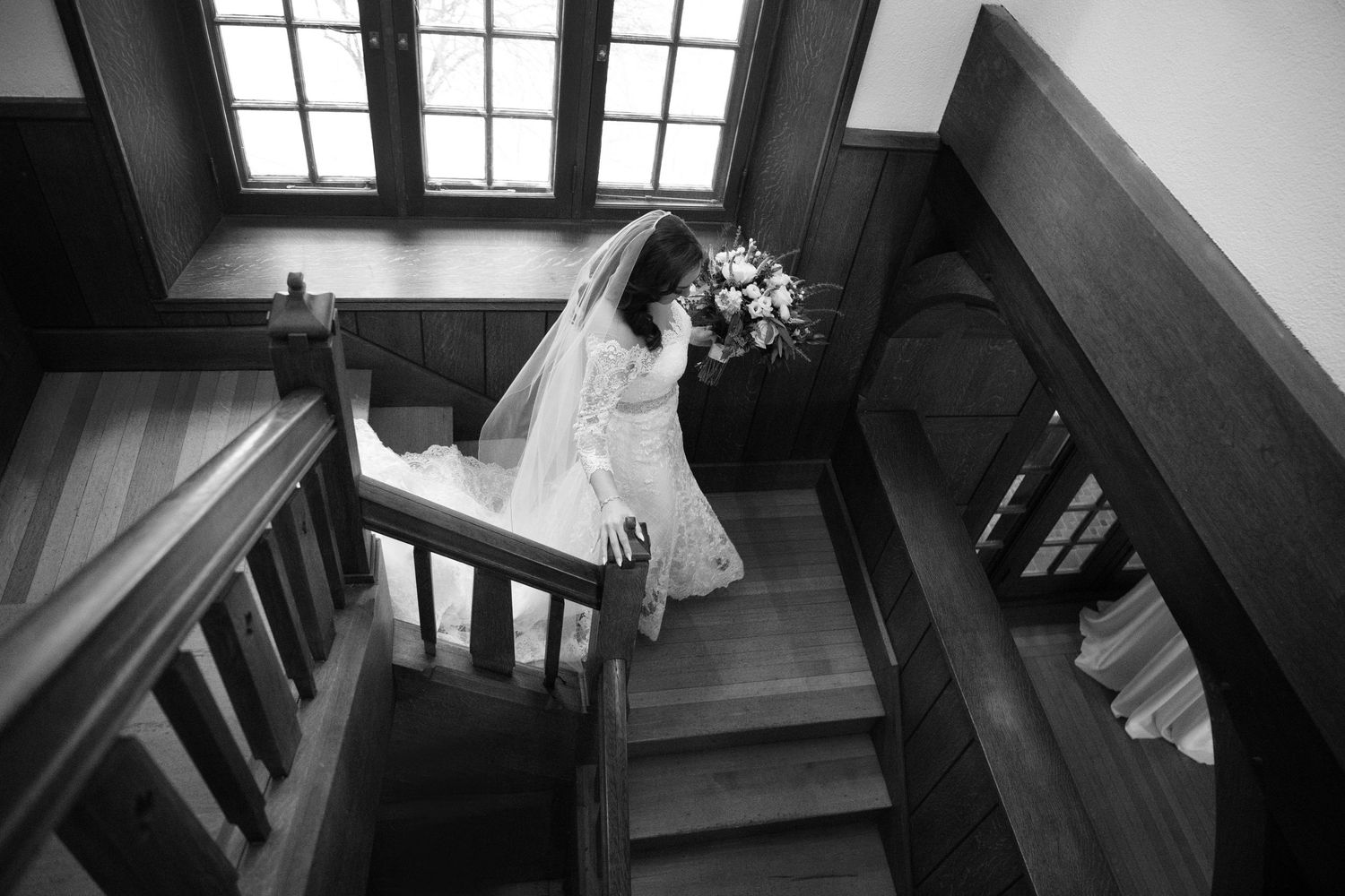 Black and white architectural photograph showing a dramatic angular staircase with wooden steps and handrails.