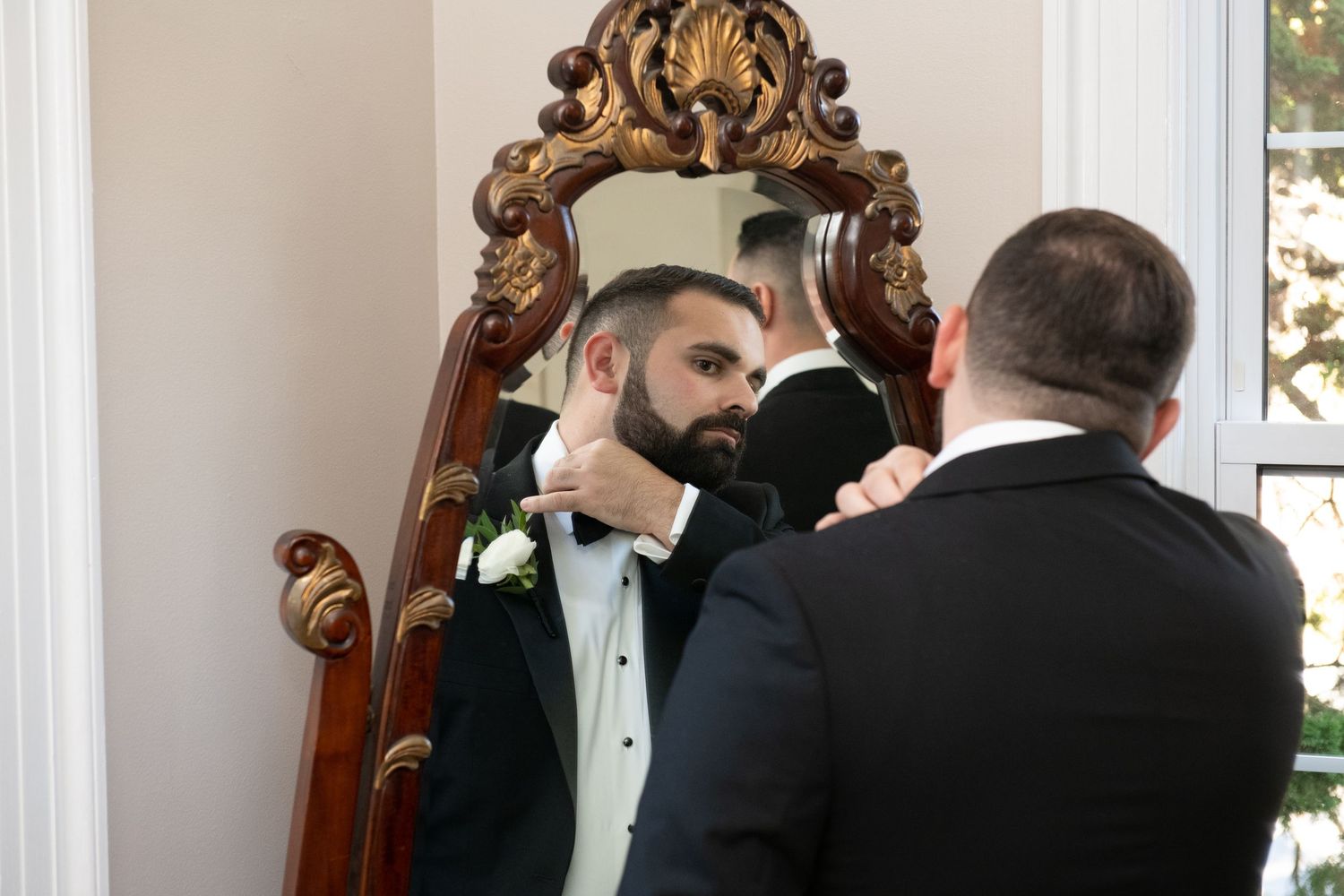Elegant wedding ceremony setup with ornate gold mirror and white floral arrangements.
