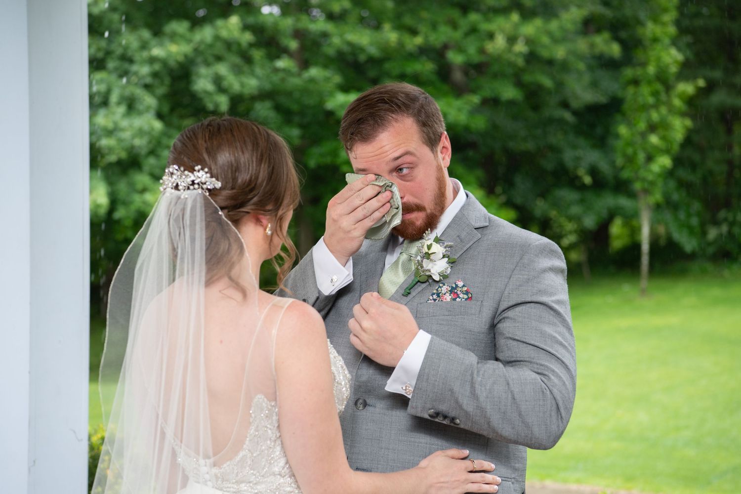 Emotional wedding moment captured between couple during their first look under white columns.