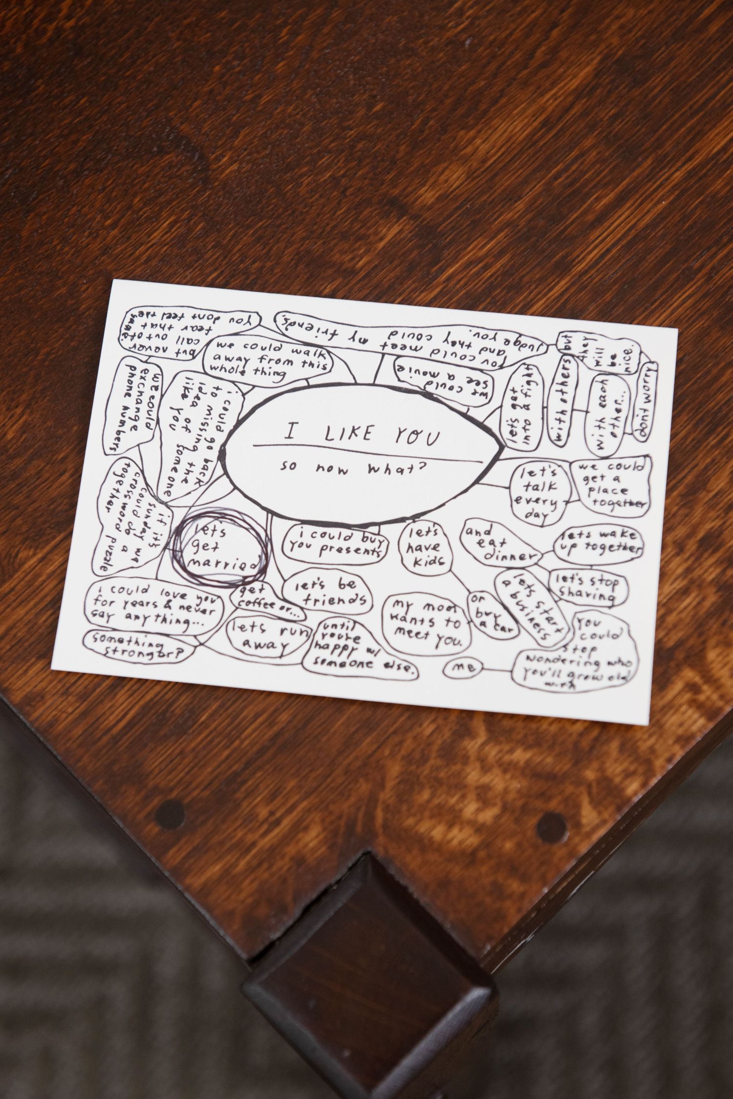 A handwritten comic strip conversation on multiple pieces of paper against a dark wooden surface.