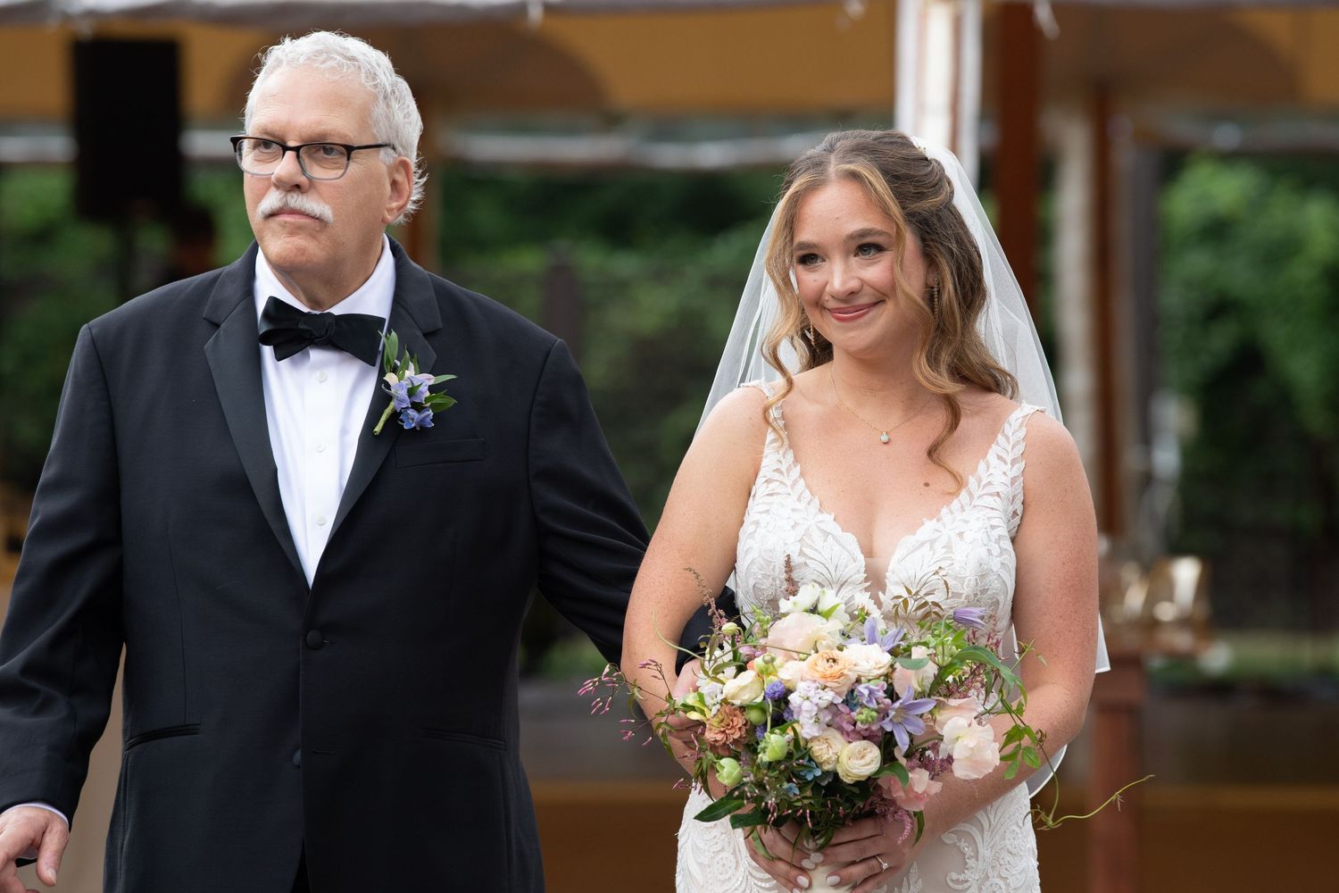 Wedding ceremony processional with formal attire and floral bouquets in an elegant venue.