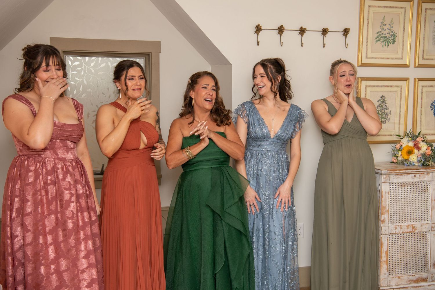 A group of bridesmaids in different colored dresses share a joyful moment together while laughing and smiling.
