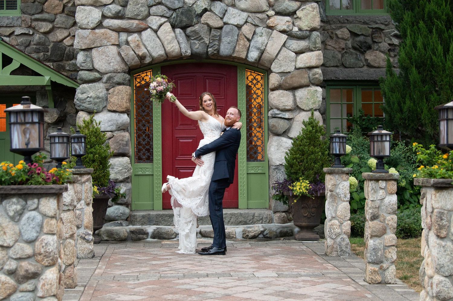 Couple sharing a romantic dip pose in front of a stone building with green door.