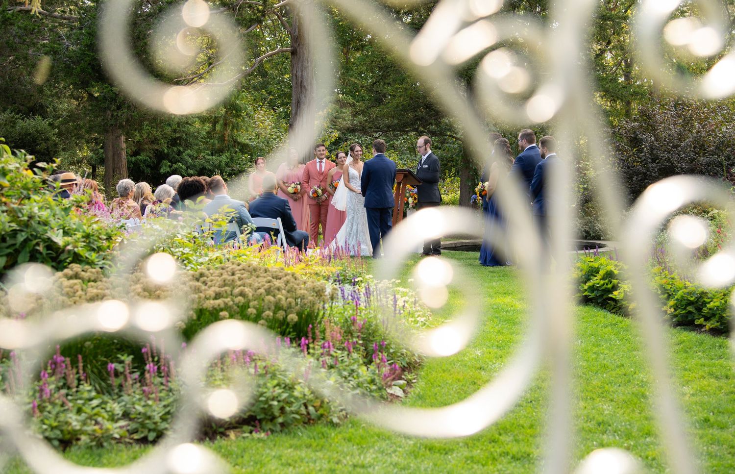 Decorative wrought iron fence with ornate scrollwork patterns frames a lush garden view in the background.