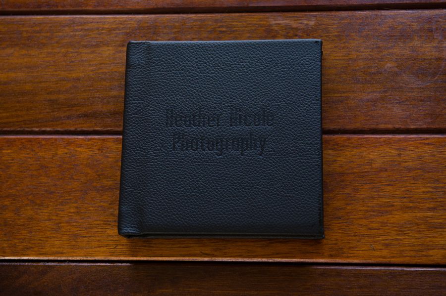 A row of black leather book covers or cases arranged on a wooden surface with dark brown staining.