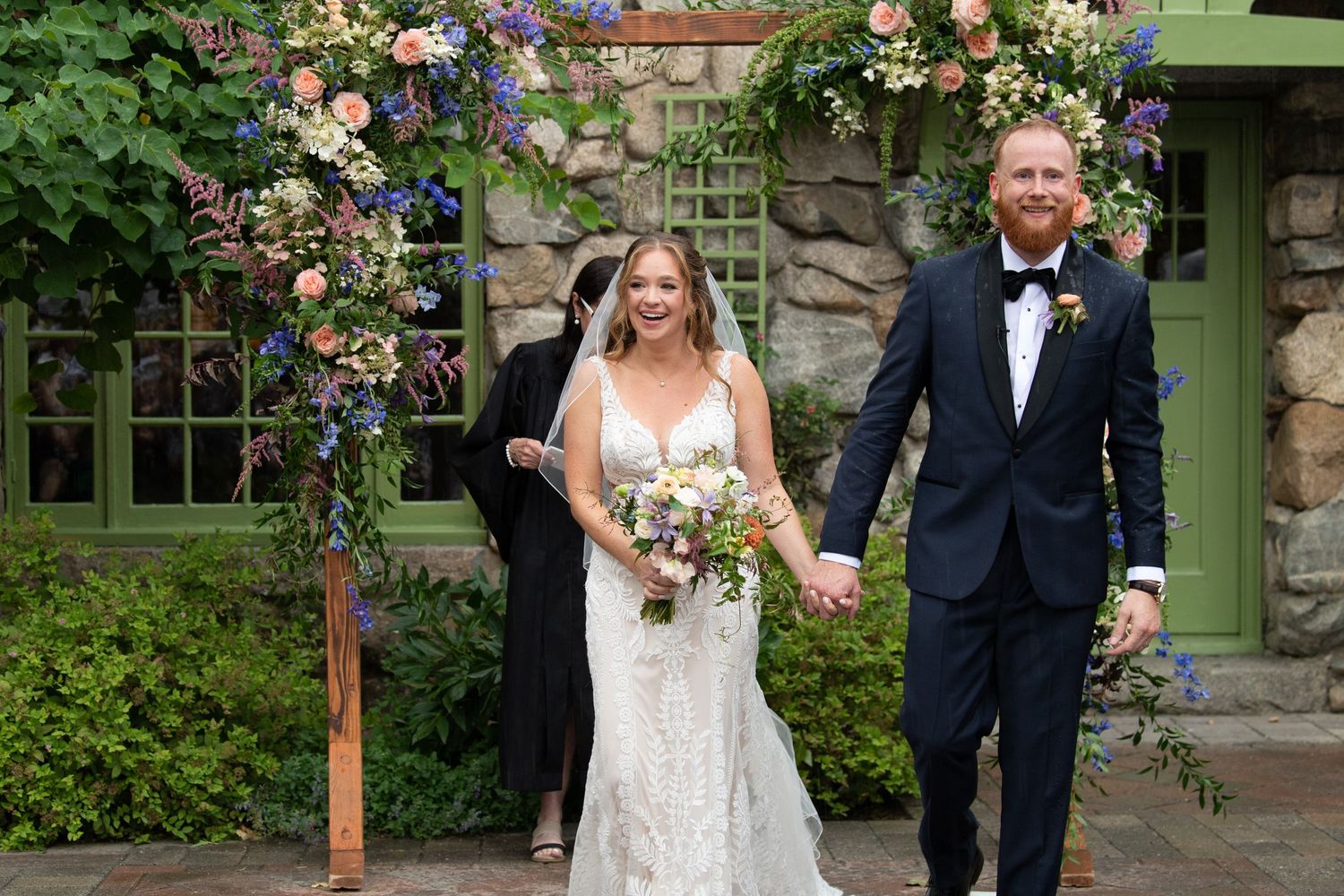 Outdoor wedding ceremony at a stone venue decorated with colorful floral arrangements.