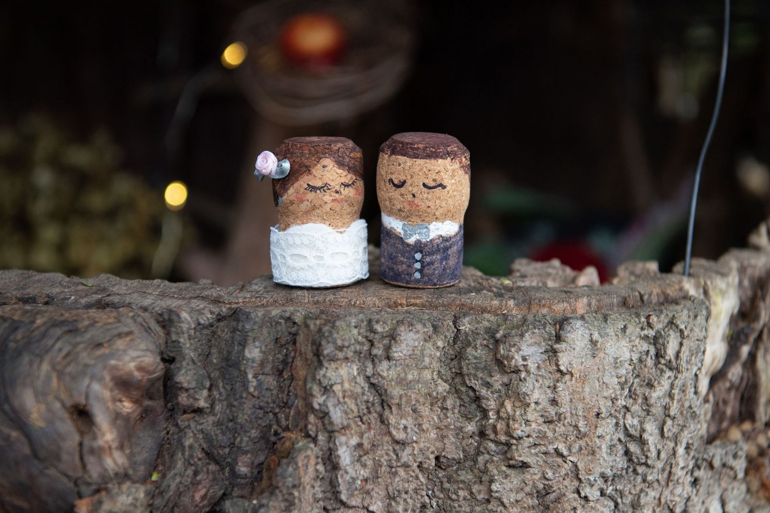 Small ceramic owl figurines arranged in a row on a rustic wooden log surface in an outdoor setting.
