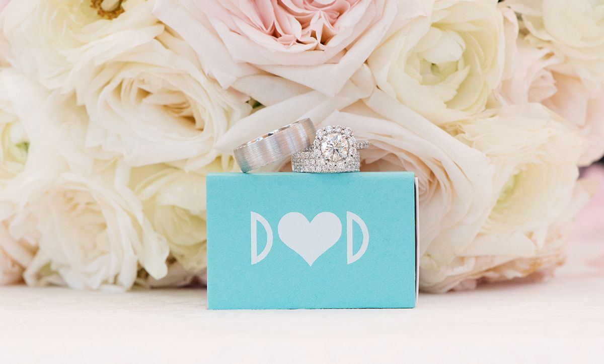 Elegant wedding decor arrangement featuring pink and white roses with turquoise accent cards against light background.