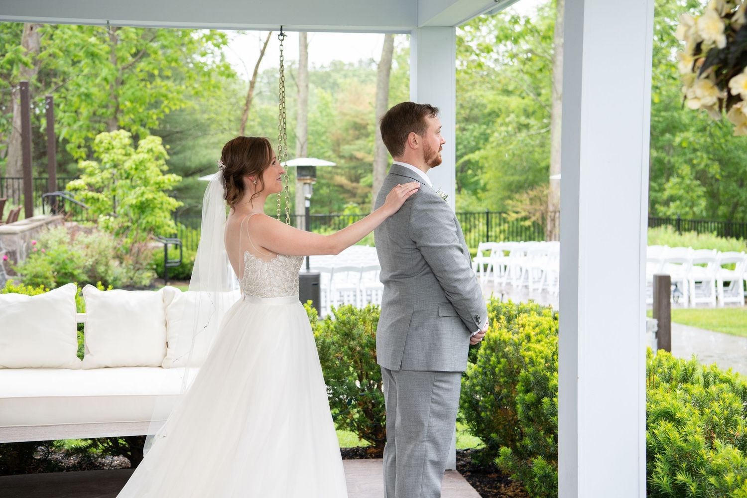 First look moment captured under a white pergola surrounded by lush green gardens.