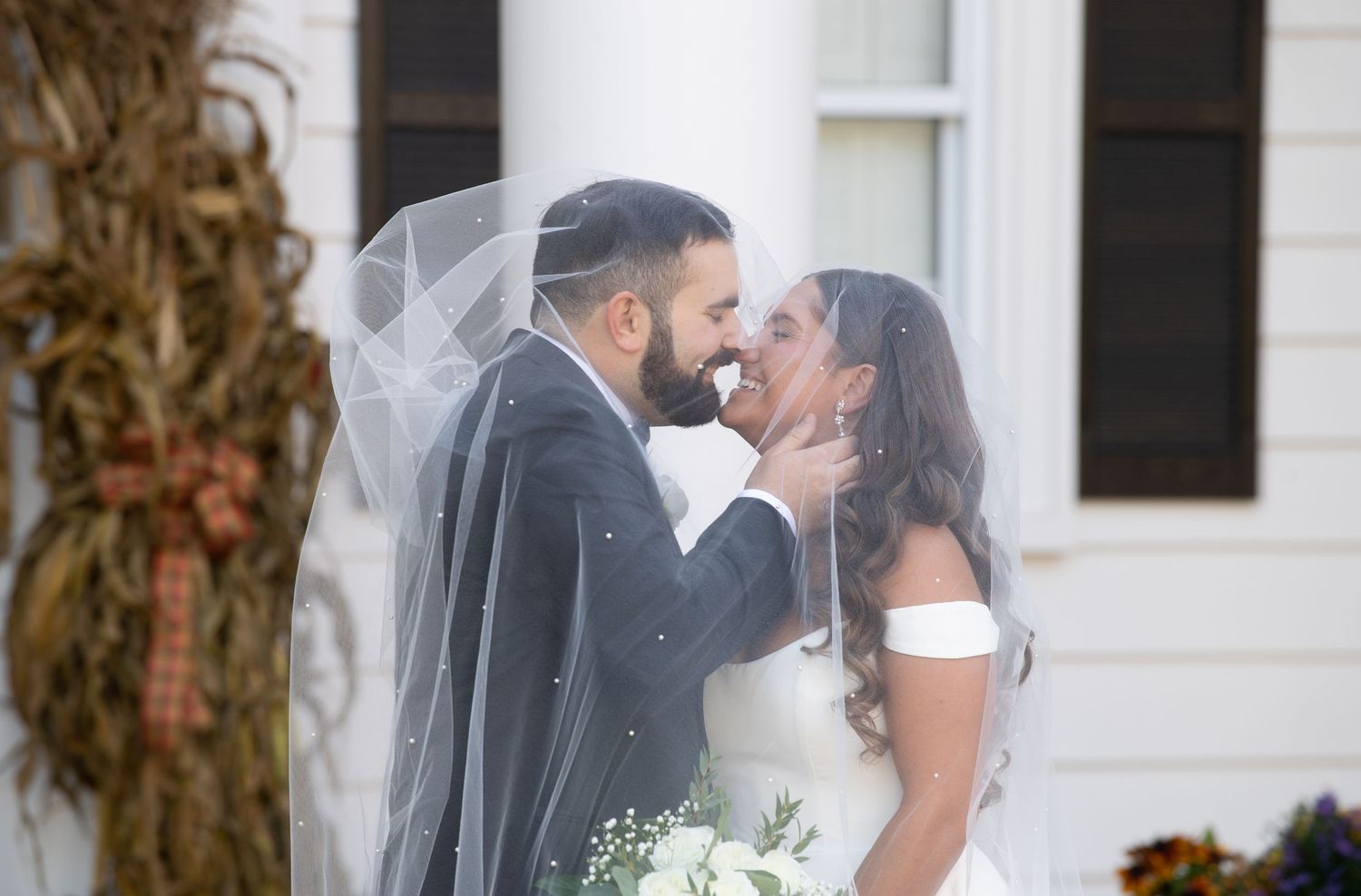 Romantic outdoor moment between newlyweds against white pillared backdrop.
