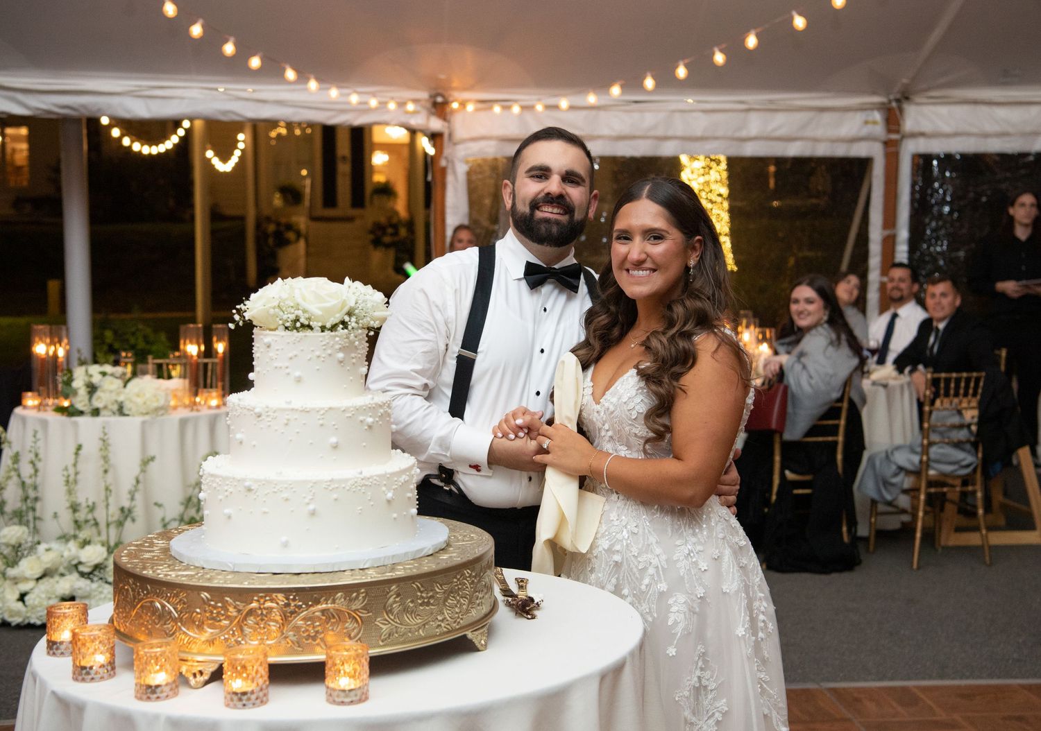 A wedding cake display with string lights and decorative elements at an elegant reception venue.