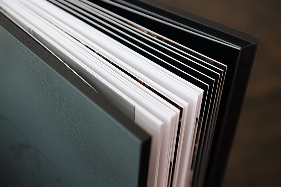 Close-up view of white pages in an open book with dark binding showing layered paper edges.