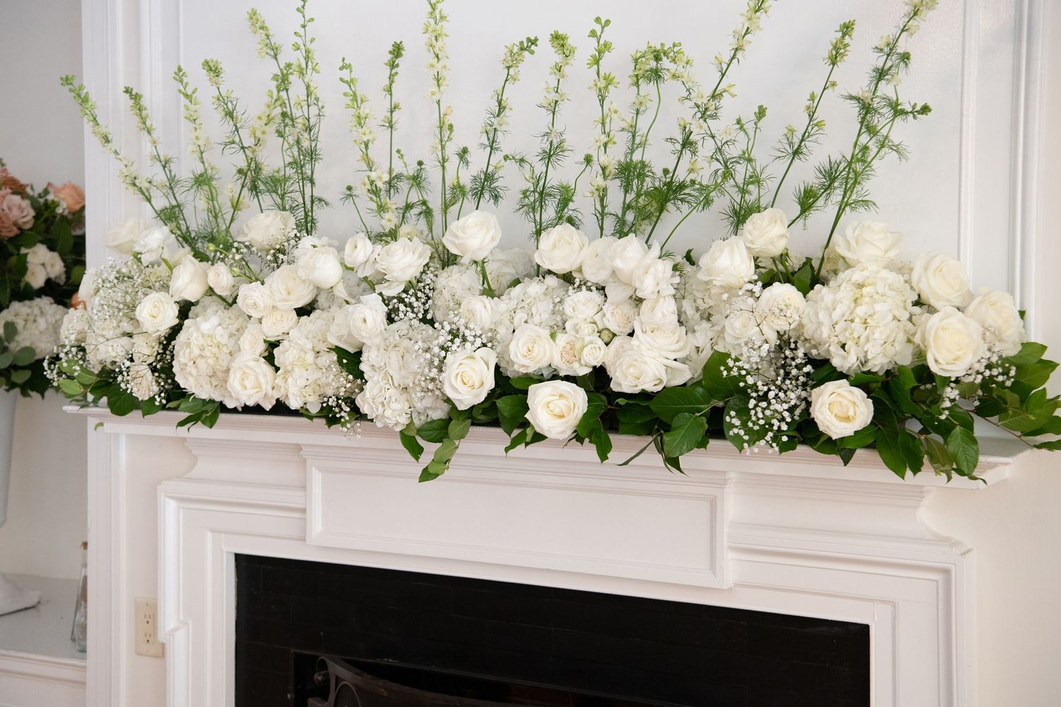 Elegant white floral arrangements with roses and greenery decorate a luxurious indoor wedding venue.