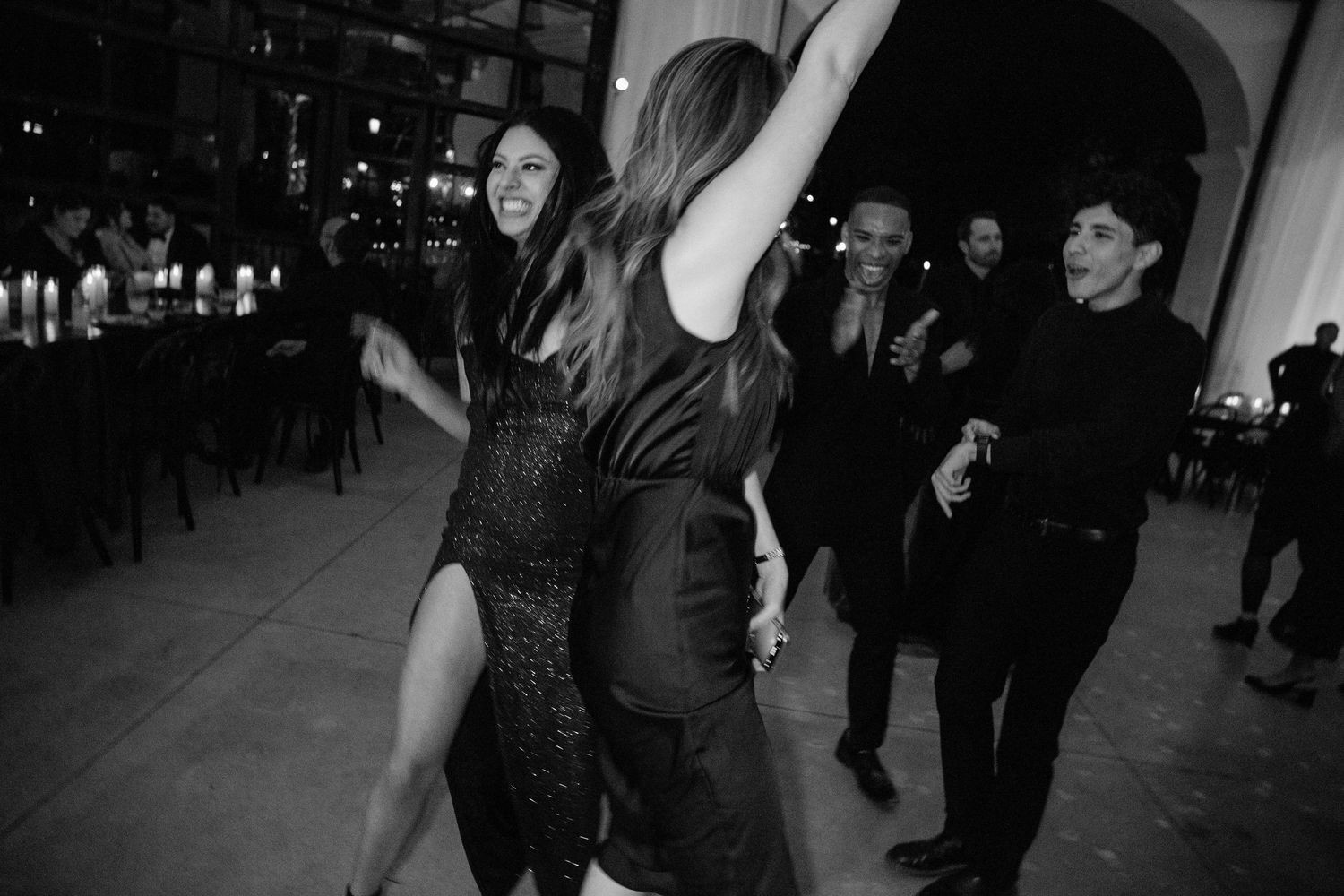People dance together in a dimly lit room during what appears to be a social dance gathering or party.