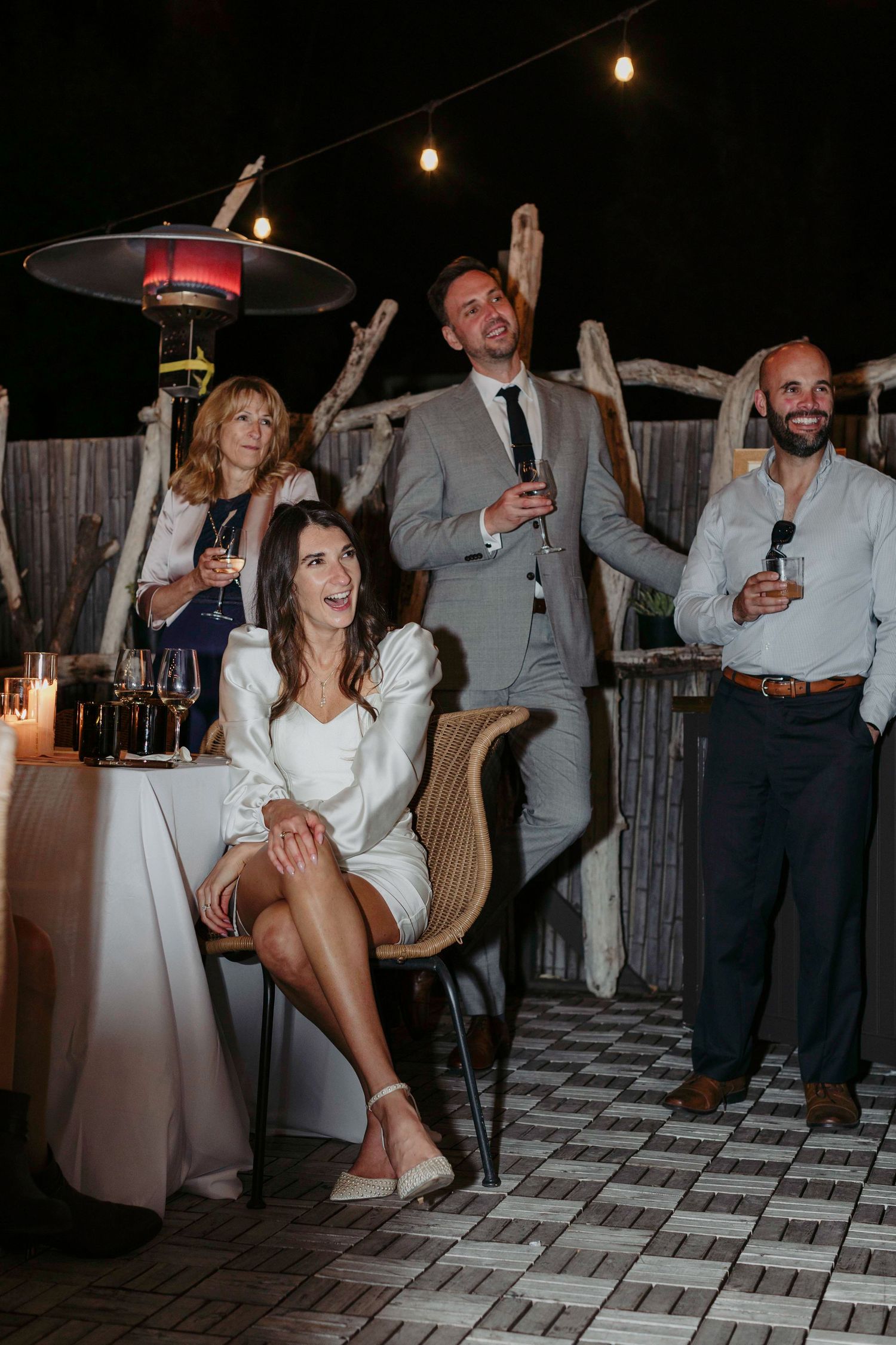 Wedding party guests dancing energetically on a checkered dance floor under string lights at an evening reception.