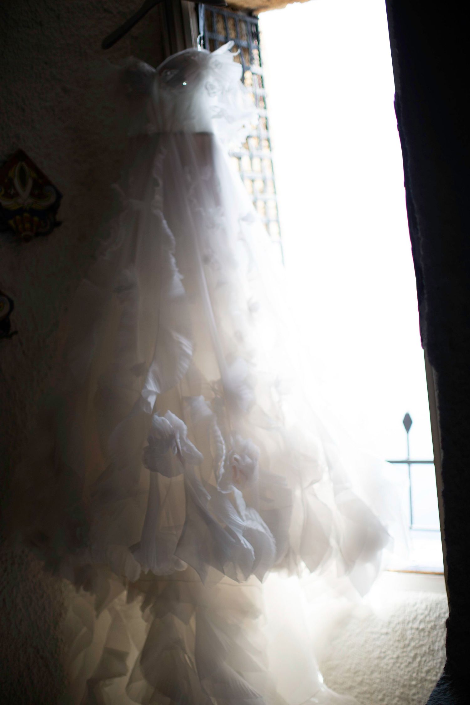 Sunlight streams through a sheer white curtain creating a soft, ethereal glow against a dark background.