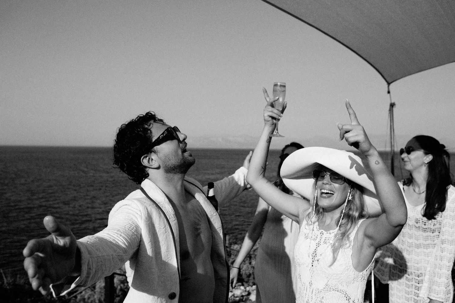 A group of people dancing and celebrating together on a boat during a sunny day at sea.