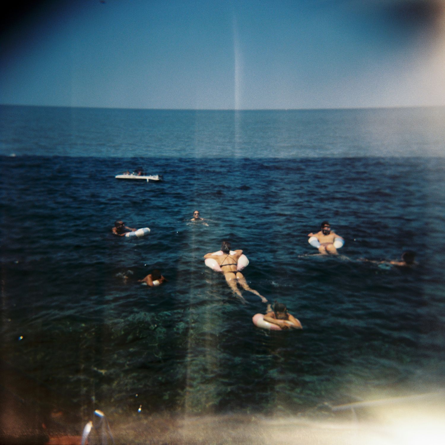 Group of people enjoying water activities in the ocean on a sunny day.