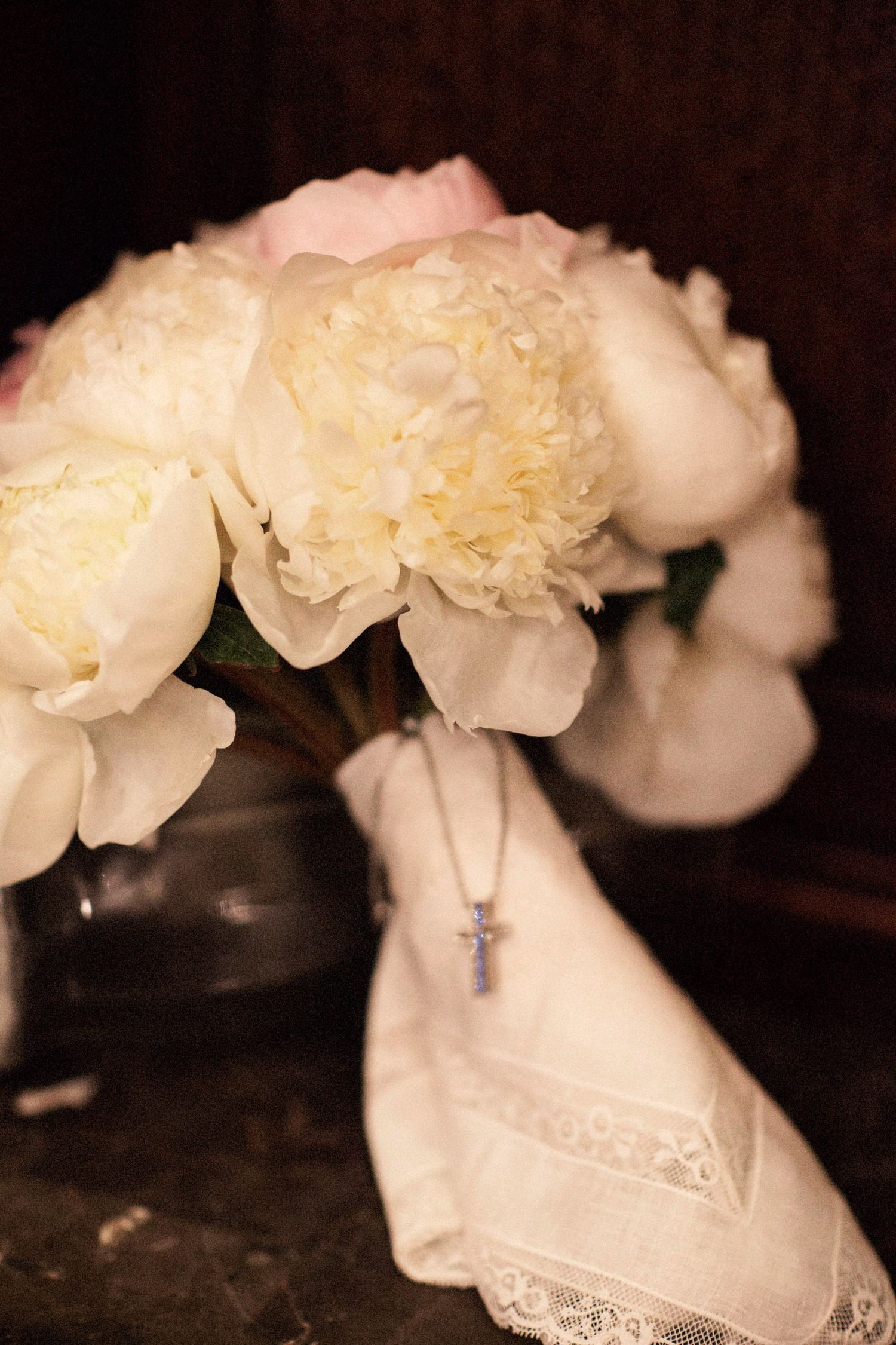 White carnations arranged in delicate lace-trimmed vases create an elegant vintage display against a dark background.