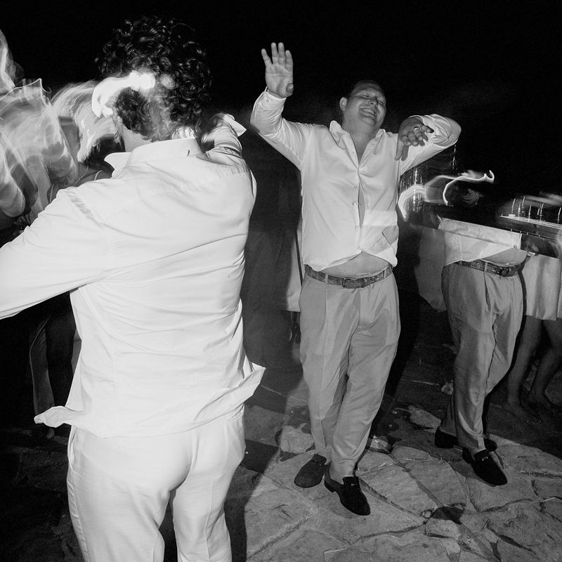A group of people dancing together at what appears to be a wedding reception or party in black and white.