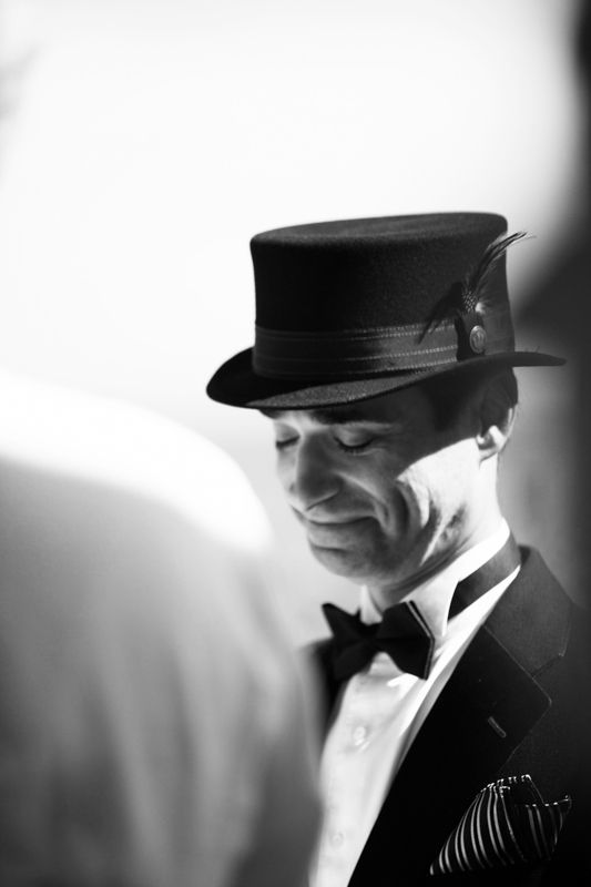 Black and white portrait of a person wearing a military-style cap and formal attire in a dramatic lighting setup.
