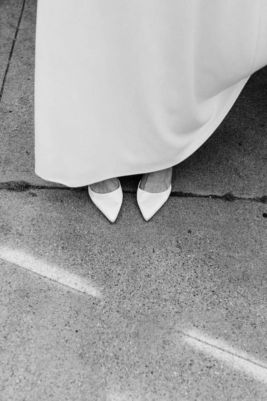 A series of black and white images showing white shoes peeking out from beneath a flowing wedding dress hem.