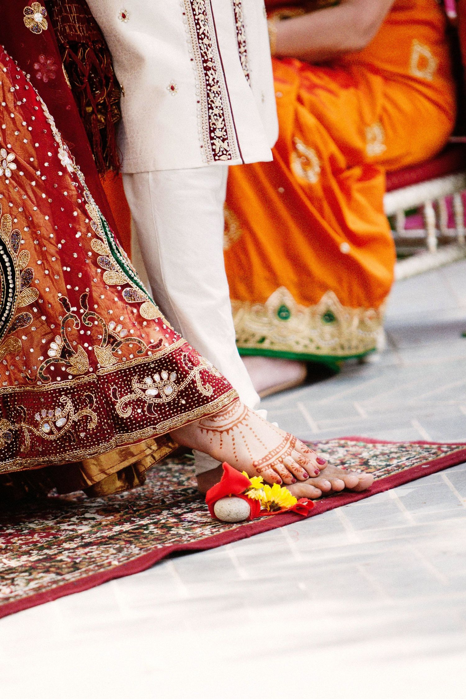 Close-up view of traditional Indian bridal feet adorned with henna and jewelry on a white floor.