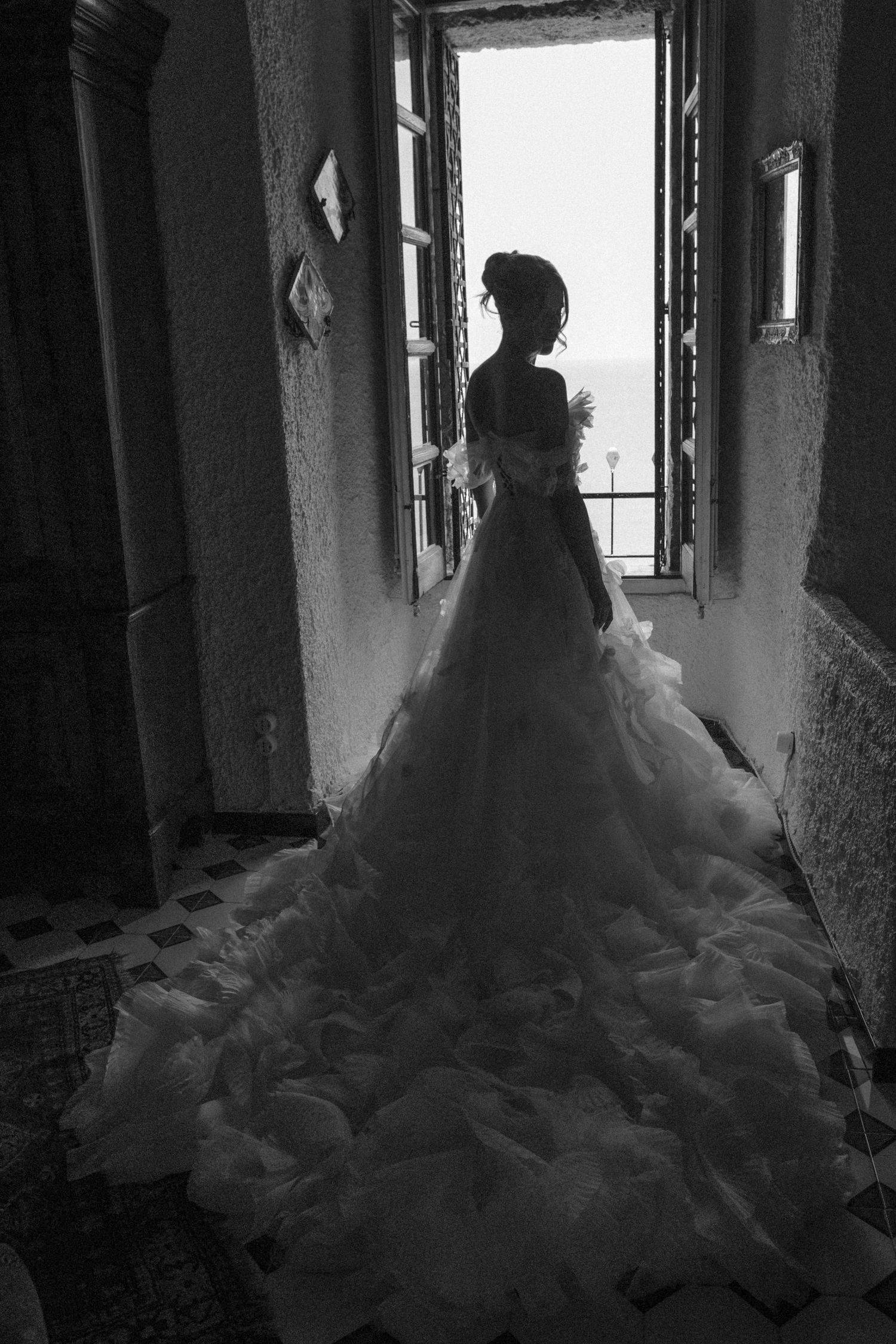 A silhouetted figure in a flowing wedding dress gazes through a window in a series of black and white photographs.