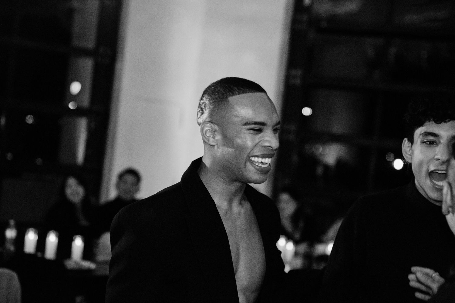 Black and white photo of people laughing and socializing at what appears to be a formal evening event.