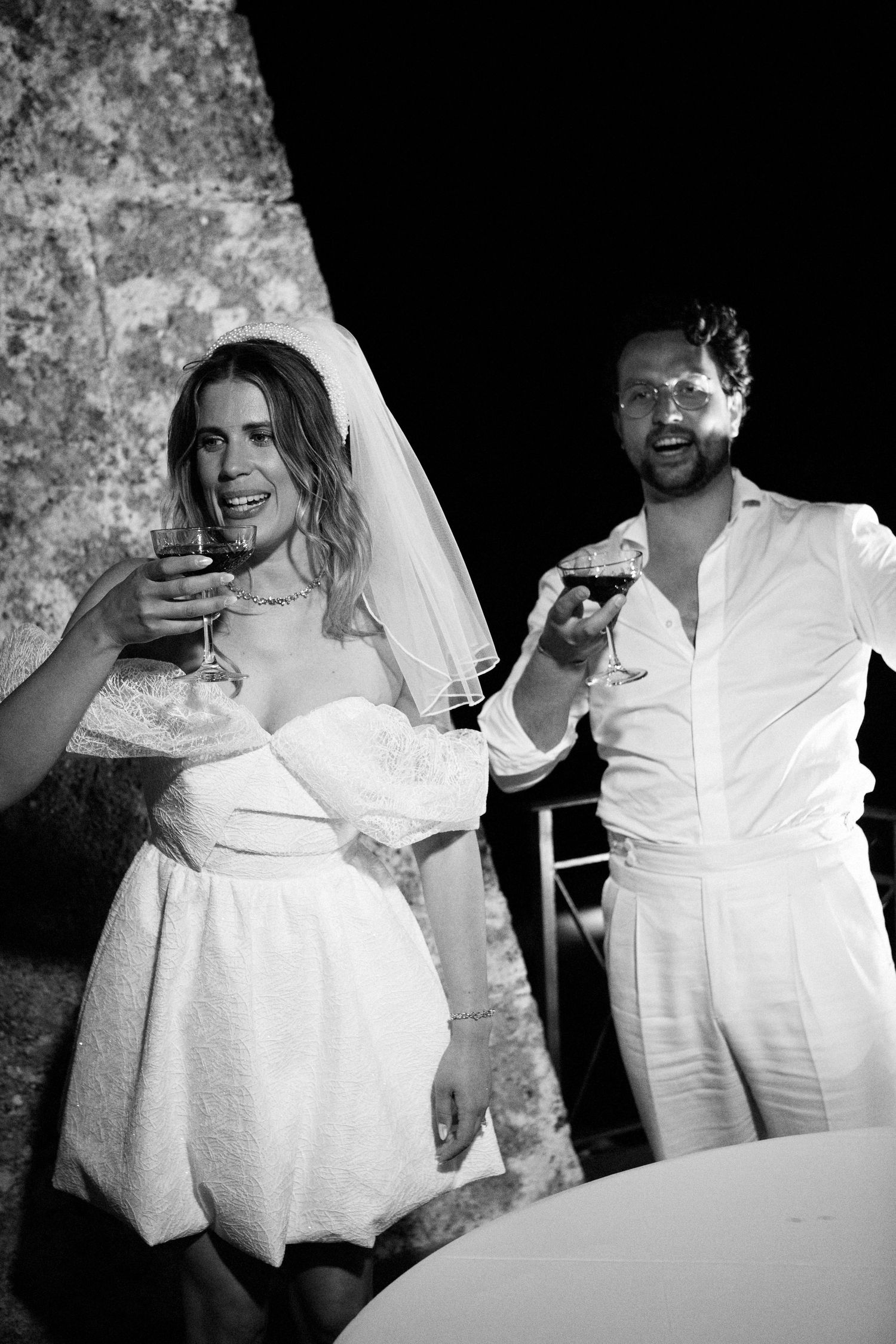 Black and white photo sequence showing two people in white wedding attire sharing joyful moments during a celebration.
