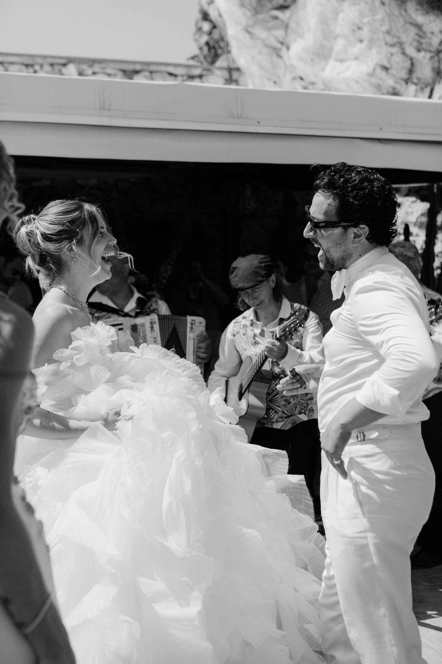 A sequence of black and white photos showing couples dancing together in formal white attire at a celebration.