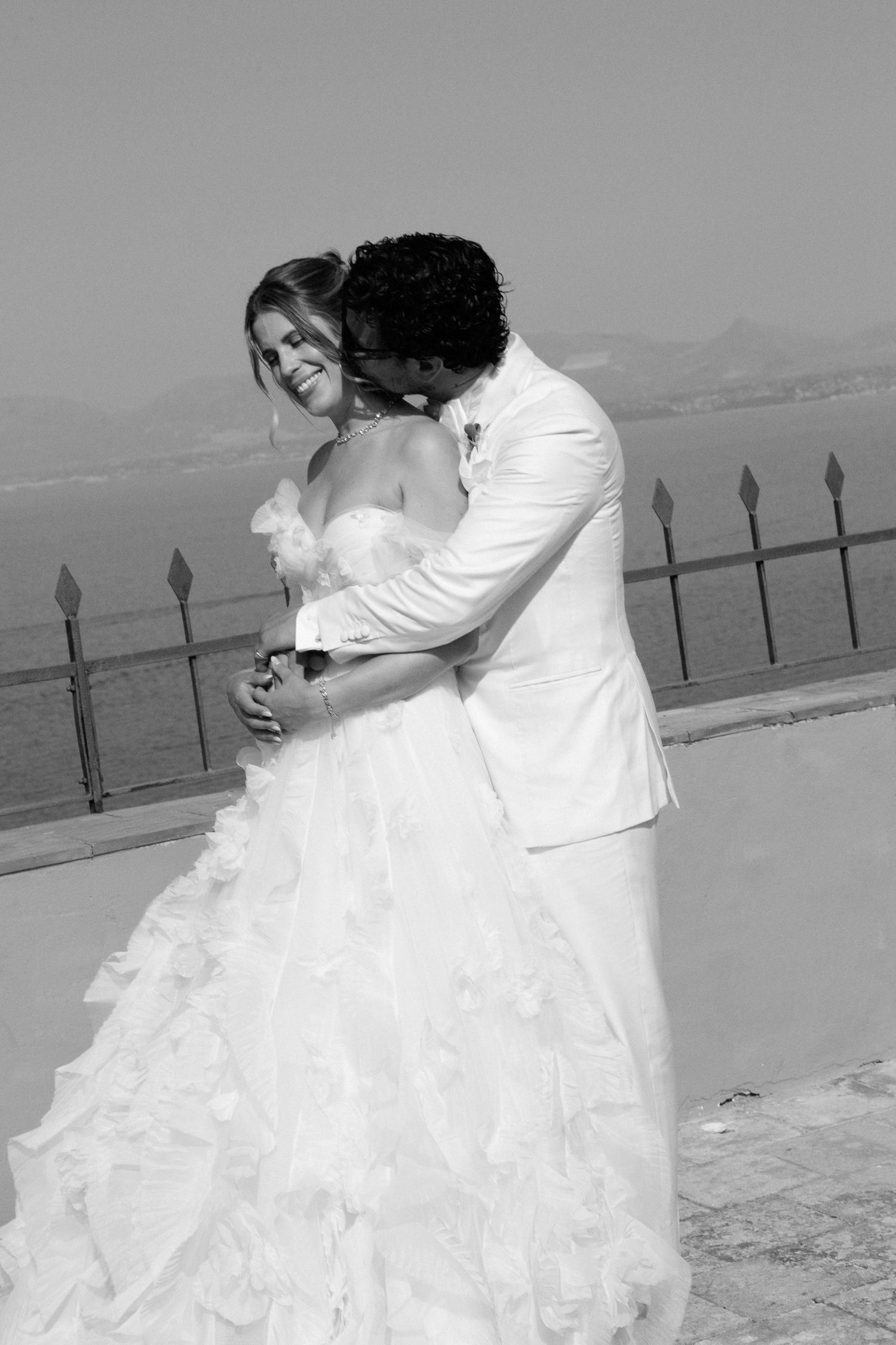 A romantic black and white photo sequence shows a couple in wedding attire embracing by the ocean.