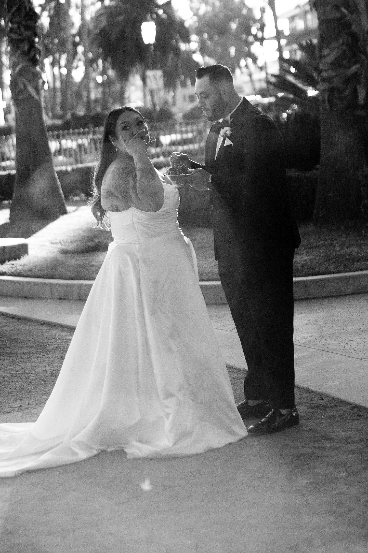 Black and white wedding photo of a couple sharing a joyful moment outdoors under hanging lanterns.