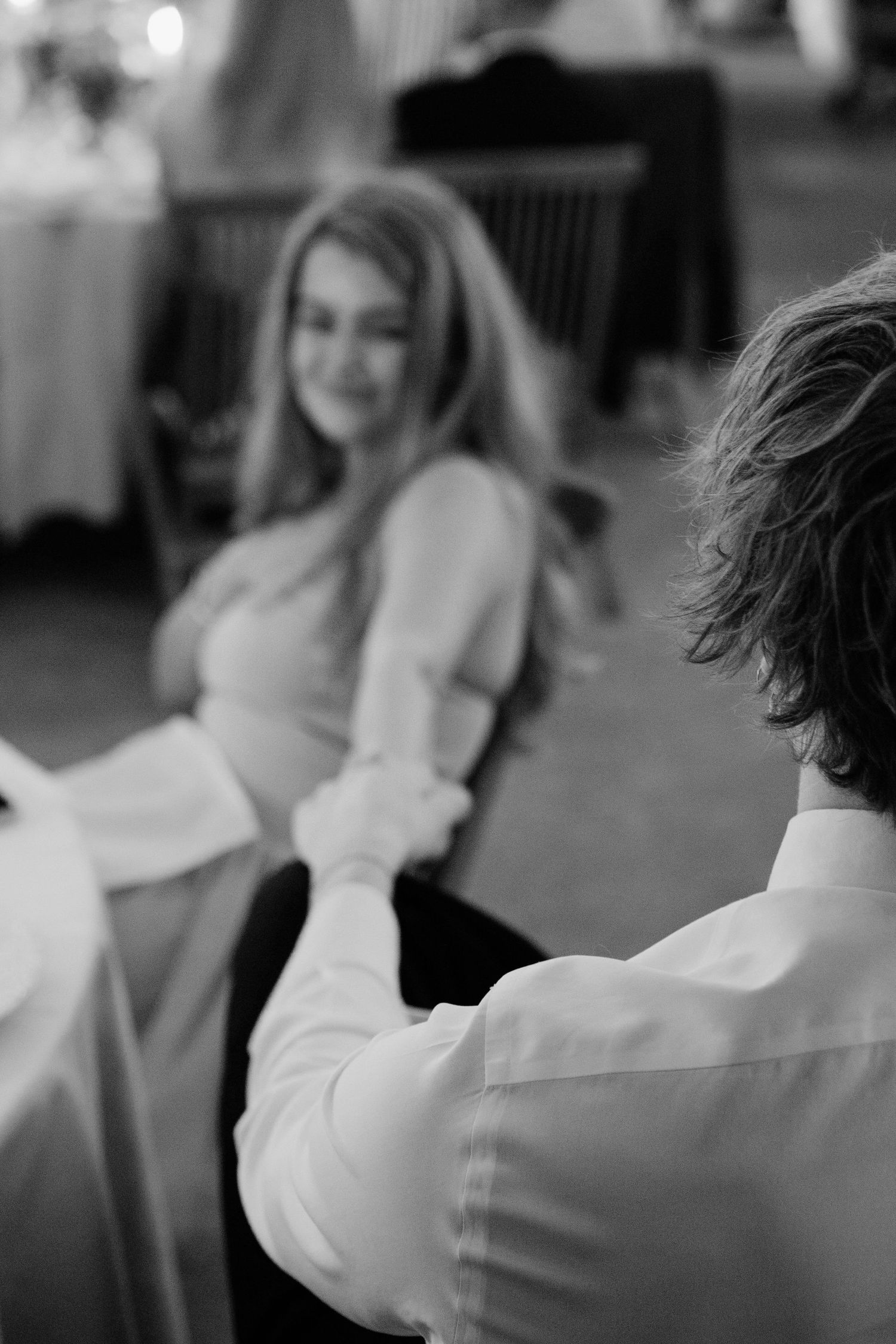 A black and white candid photo of two people in conversation at a formal event.
