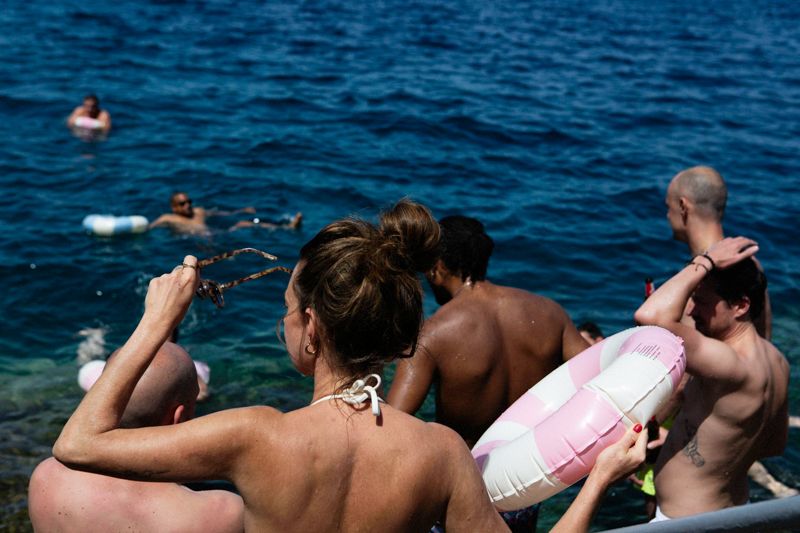A sequence of people diving and swimming in deep blue ocean water during a summer day.