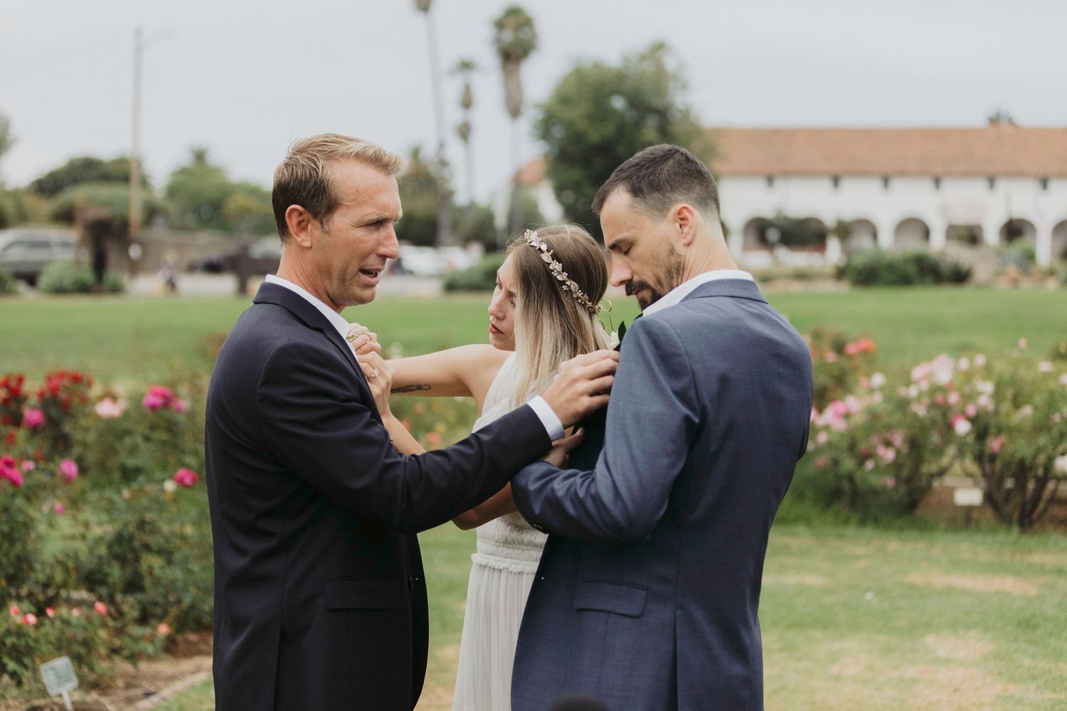 Two people in formal attire share a joyful moment together in a garden setting with roses in the background.