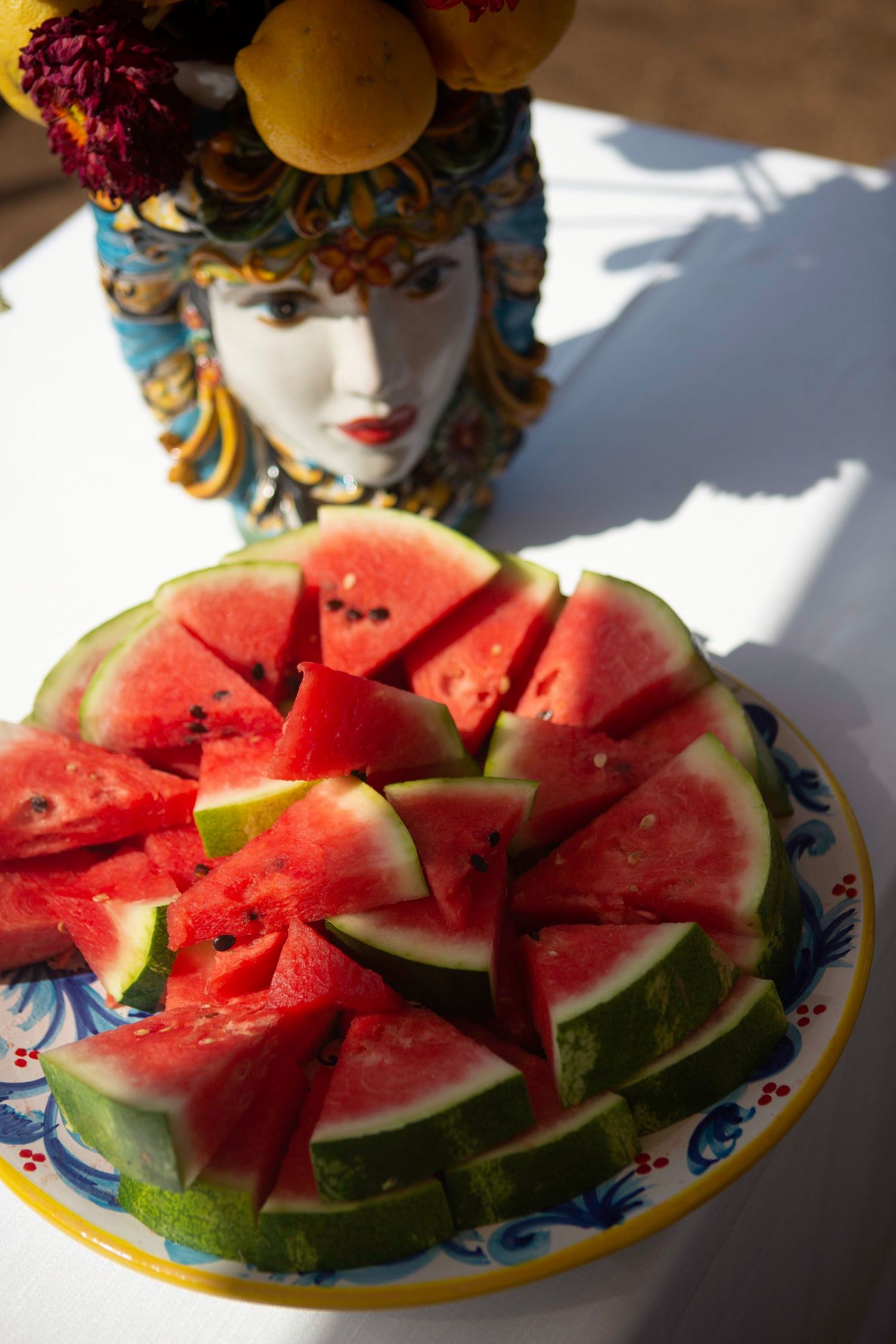 Fresh juicy watermelon slices arranged on a decorative plate with blue and yellow floral pattern in natural lighting.