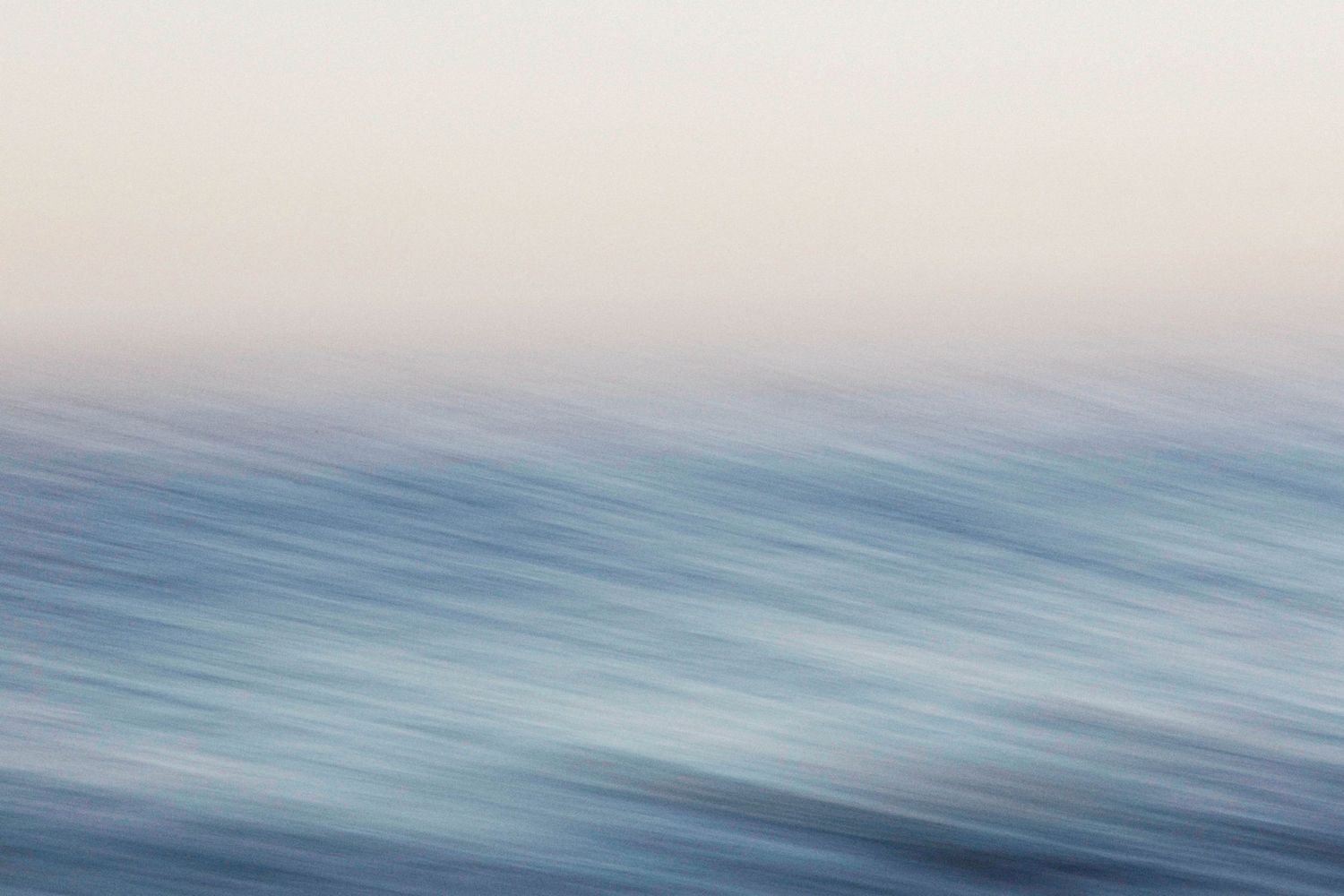 Abstract motion blur ocean seascape with soft blue waves and pastel pink sky creating a dreamy, serene coastal scene.