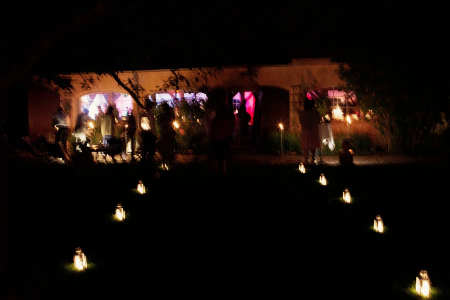 A row of glowing lanterns illuminates an outdoor pathway at night creating a warm and inviting atmosphere.