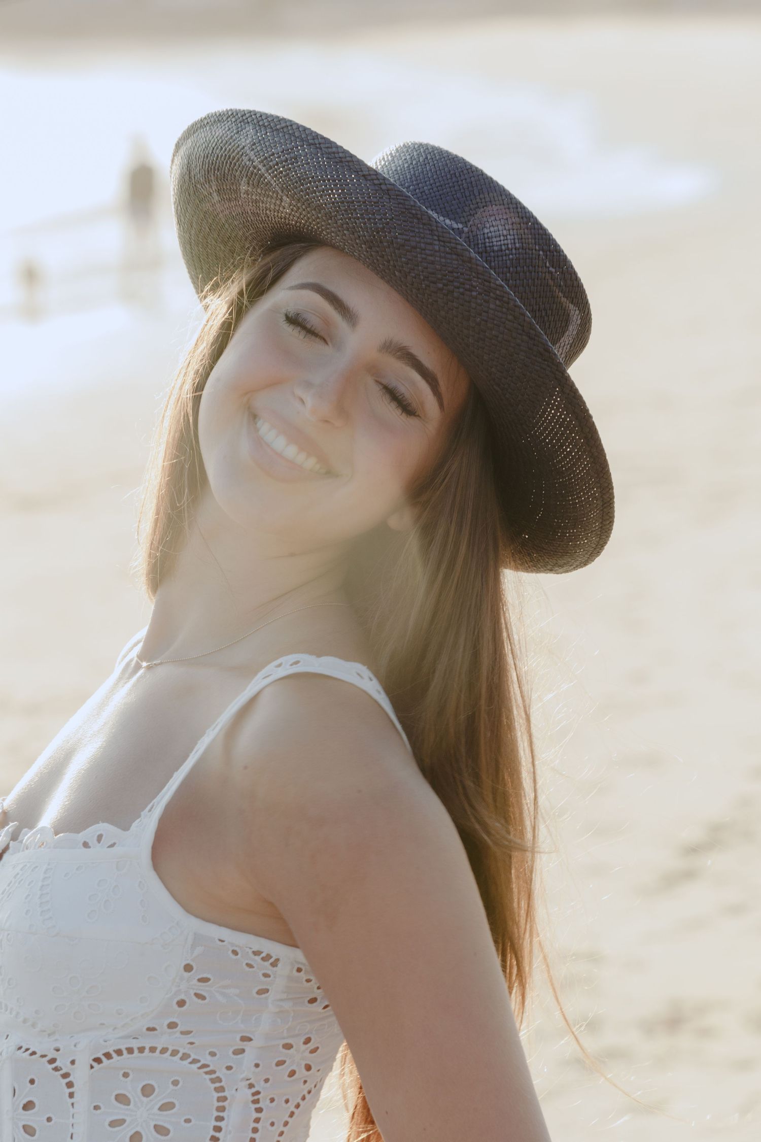 A person wearing a black cowboy hat and white lace top poses against a bright background in a carefree manner.
