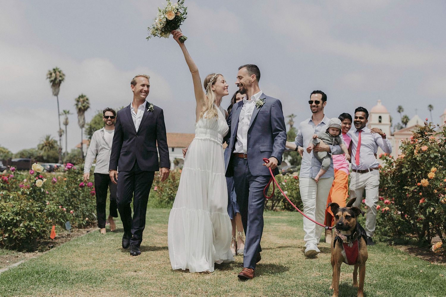 A couple shares a romantic moment in a garden filled with blooming roses on their wedding day.