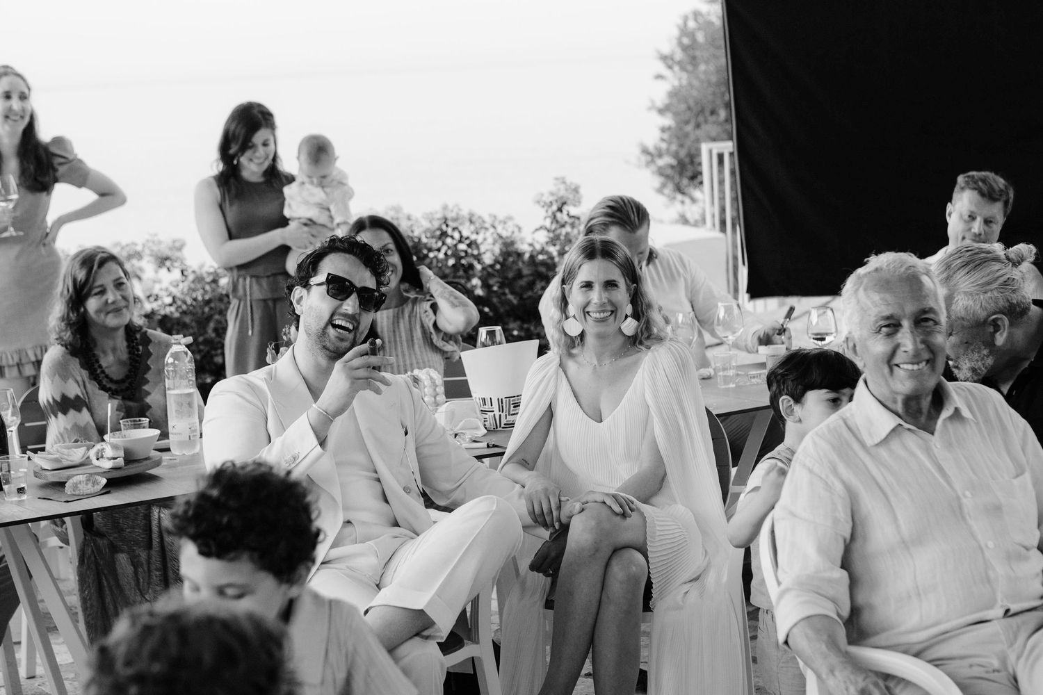 A black and white collage strip showing multiple candid moments of people laughing and interacting at what appears to be a party.