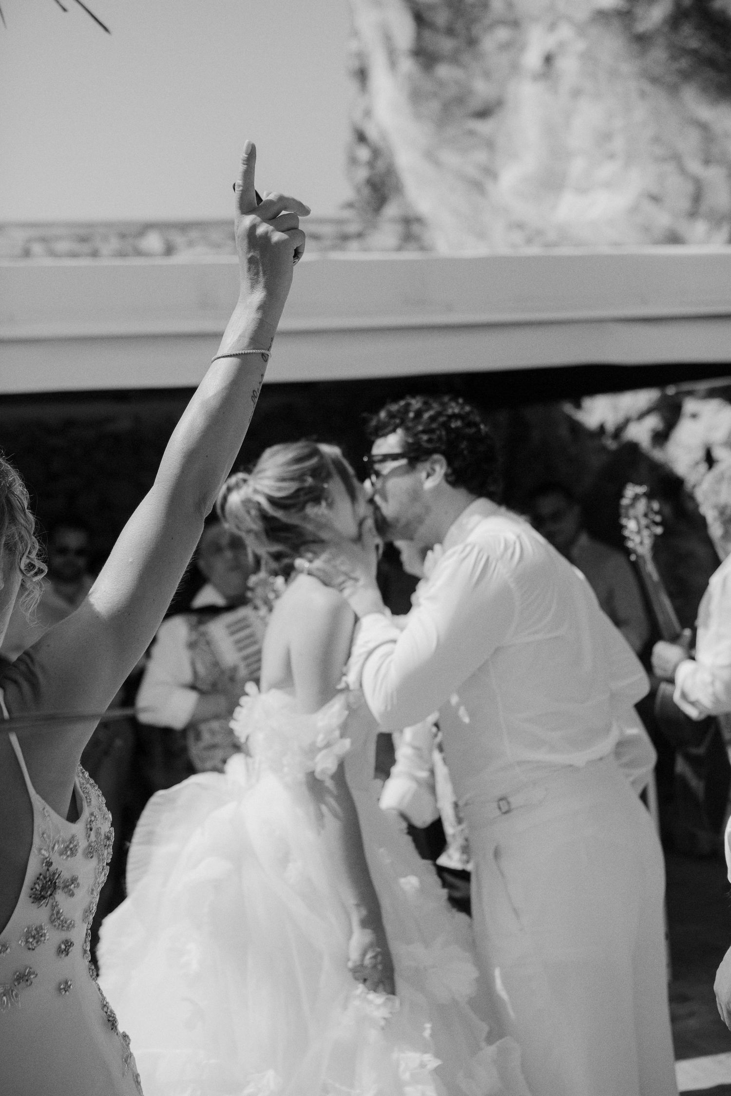 Black and white photo of a bride and groom sharing their first kiss at an outdoor wedding ceremony.