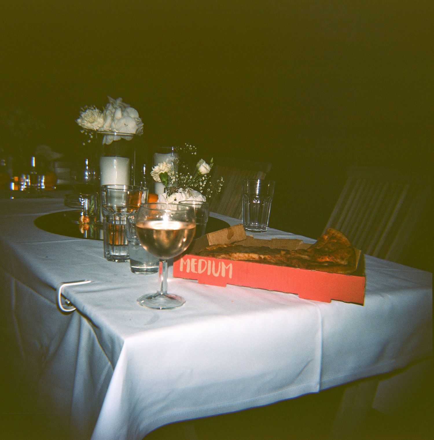 Table settings with glowing candles and wine glasses on white tablecloths in a dimly lit restaurant.