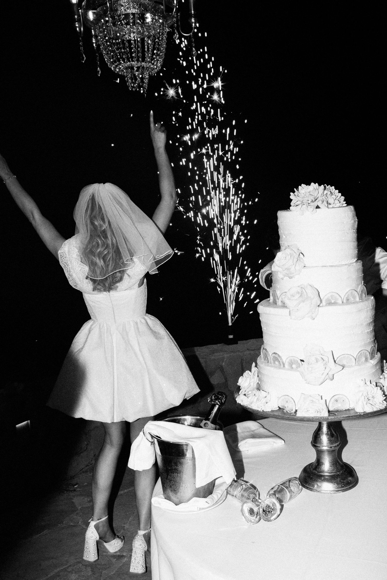 A series of black and white photos showing sparklers and a wedding cake at a reception celebration.